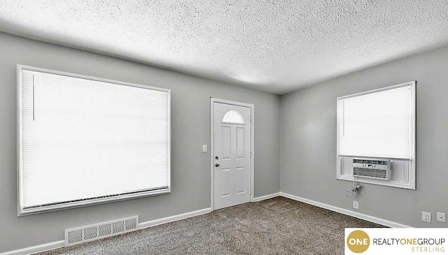 carpeted entrance foyer featuring cooling unit and a textured ceiling