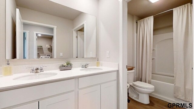 full bathroom featuring toilet, hardwood / wood-style flooring, shower / bathtub combination with curtain, and vanity