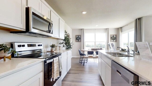 kitchen with appliances with stainless steel finishes, white cabinets, a healthy amount of sunlight, and sink