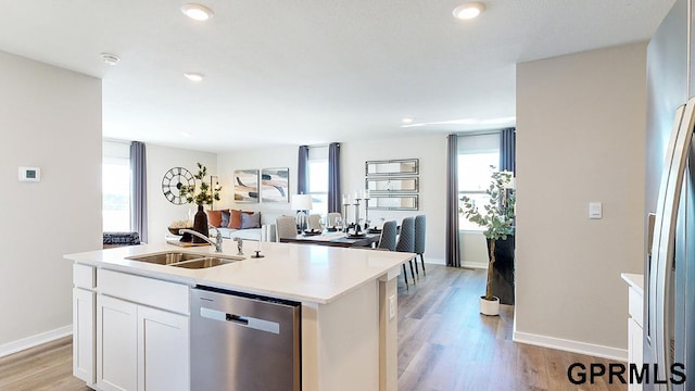 kitchen with a healthy amount of sunlight, dishwasher, an island with sink, and white cabinets