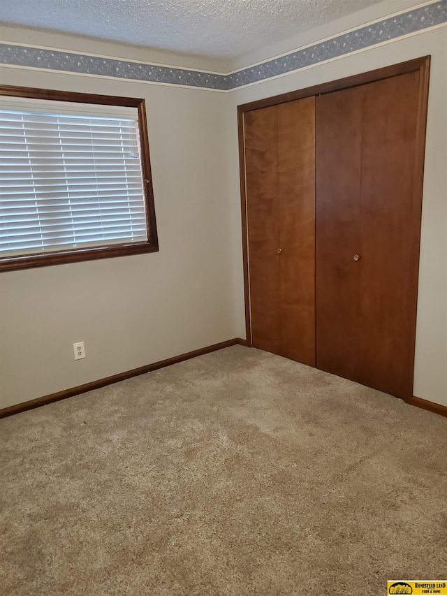 unfurnished bedroom featuring a closet, carpet flooring, and a textured ceiling