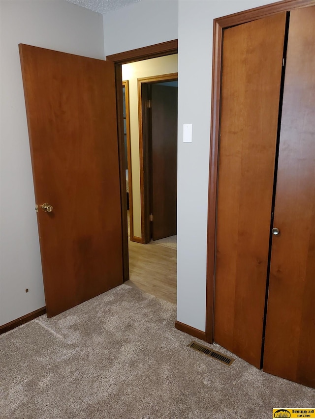 unfurnished bedroom with light carpet, a closet, and a textured ceiling