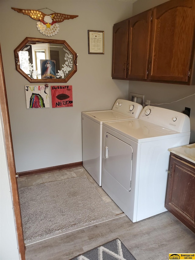 washroom featuring cabinets, independent washer and dryer, and light hardwood / wood-style flooring