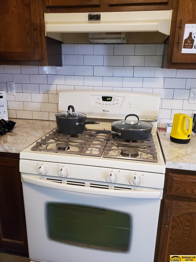 kitchen with decorative backsplash, white range with gas cooktop, and dark brown cabinets