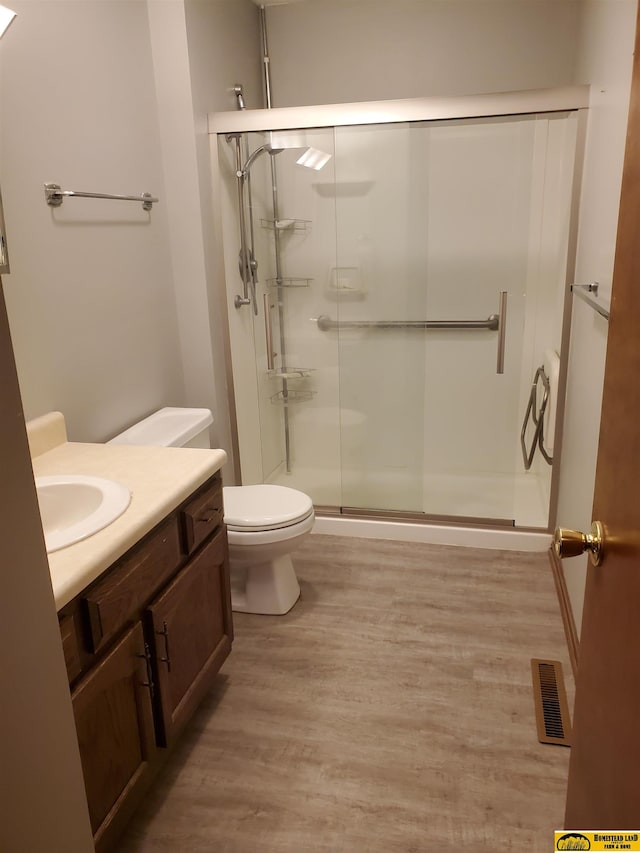 bathroom with vanity, toilet, hardwood / wood-style flooring, and an enclosed shower