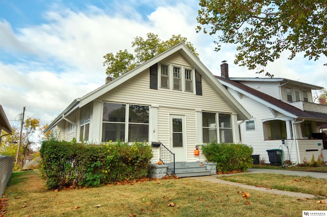 bungalow-style house featuring a sunroom and a front lawn