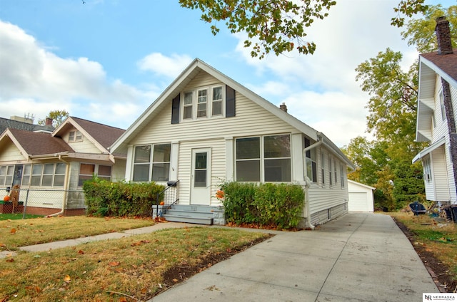 view of front of house with a front yard, an outbuilding, a garage, and a sunroom