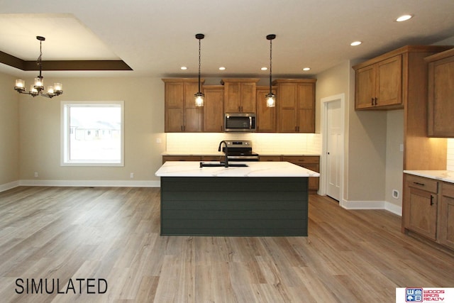 kitchen featuring decorative light fixtures, a kitchen island with sink, stainless steel appliances, and sink