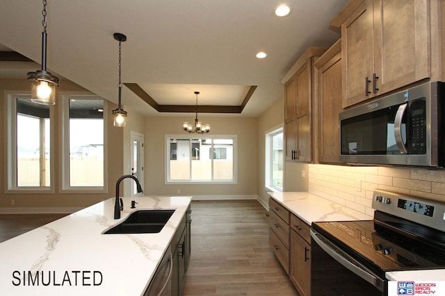 kitchen with sink, appliances with stainless steel finishes, hanging light fixtures, and hardwood / wood-style flooring