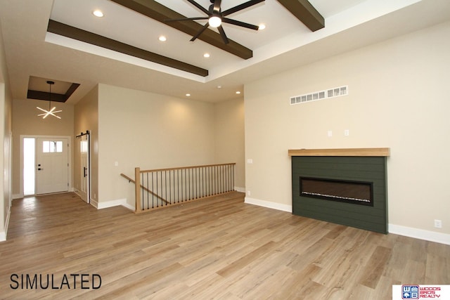 unfurnished living room with light hardwood / wood-style flooring, beamed ceiling, a high ceiling, and a raised ceiling