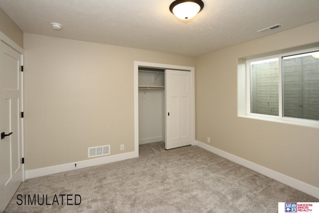 unfurnished bedroom with light carpet, a closet, and a textured ceiling