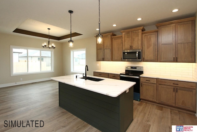 kitchen featuring a kitchen island with sink, light hardwood / wood-style flooring, stainless steel appliances, sink, and pendant lighting