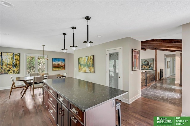 kitchen featuring dark wood-type flooring, hanging light fixtures, a textured ceiling, and a kitchen island