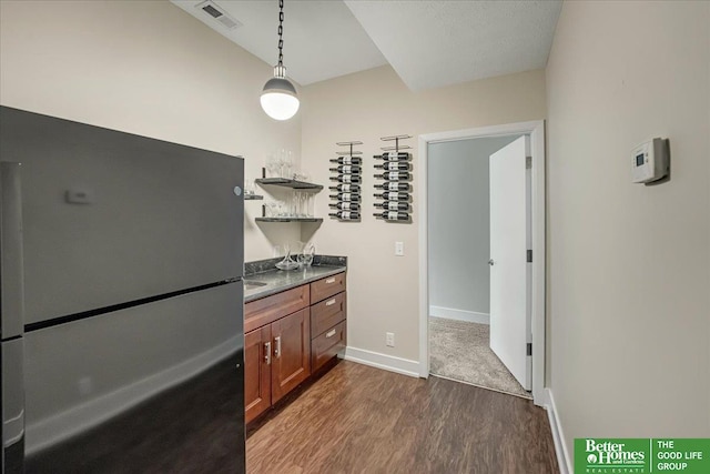 kitchen with dark wood-type flooring, decorative light fixtures, and fridge