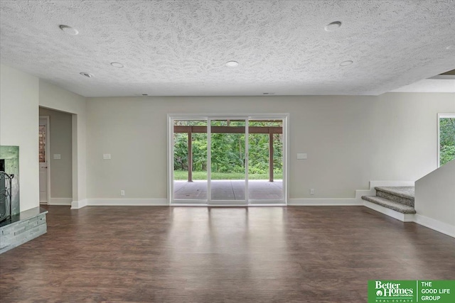 unfurnished living room with a textured ceiling and dark hardwood / wood-style flooring