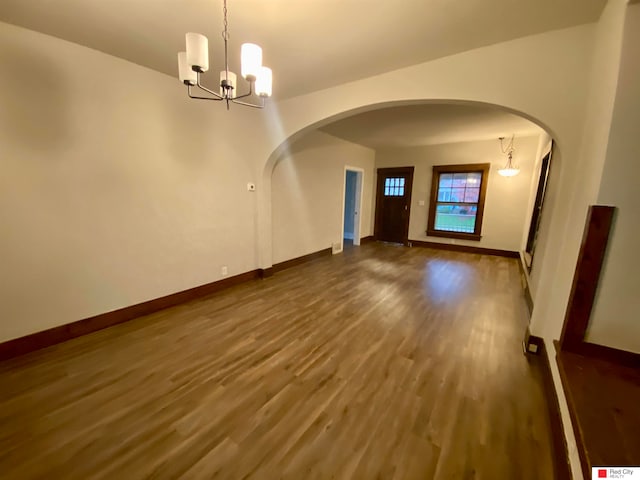 spare room with dark hardwood / wood-style floors and a chandelier