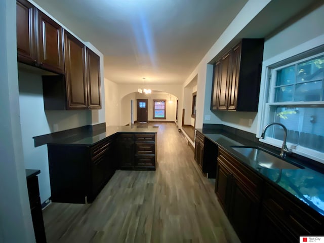 kitchen with dark brown cabinetry, sink, an inviting chandelier, light hardwood / wood-style floors, and decorative light fixtures