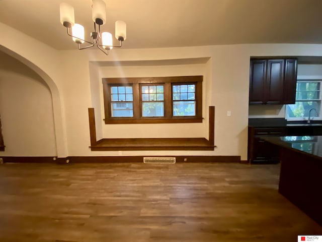 unfurnished dining area featuring sink, dark hardwood / wood-style floors, and a notable chandelier