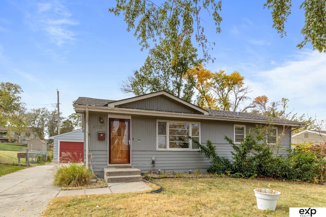 bungalow-style house featuring an outdoor structure, a garage, and a front lawn