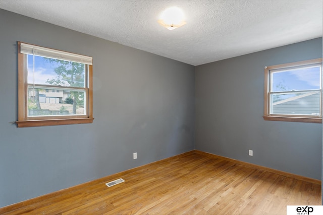 empty room with a textured ceiling and light wood-type flooring