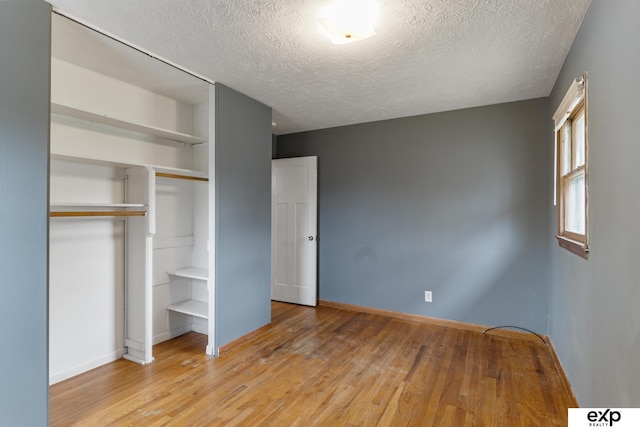 unfurnished bedroom with a closet, a textured ceiling, and light hardwood / wood-style floors