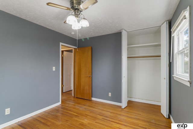 unfurnished bedroom featuring a closet, ceiling fan, a textured ceiling, and light wood-type flooring