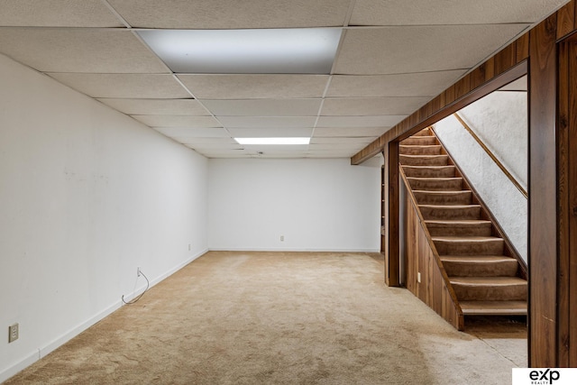 basement with a paneled ceiling and light colored carpet