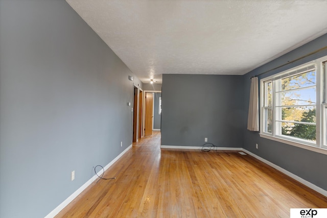 unfurnished room with light hardwood / wood-style floors and a textured ceiling