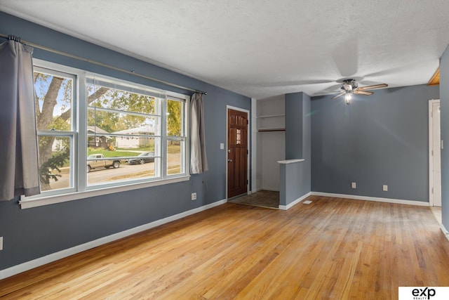 unfurnished living room with a textured ceiling, light wood-type flooring, and ceiling fan