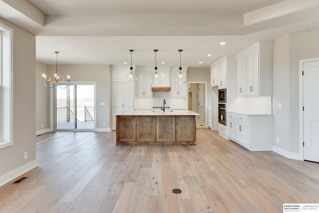 kitchen with pendant lighting, stainless steel oven, white cabinets, and a spacious island