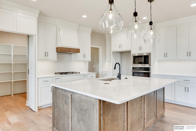 kitchen with a spacious island, built in microwave, sink, oven, and white cabinets