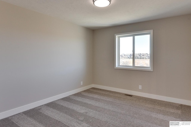 carpeted spare room featuring a textured ceiling