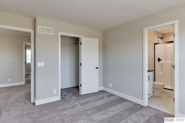 unfurnished bedroom with connected bathroom, a spacious closet, and light colored carpet