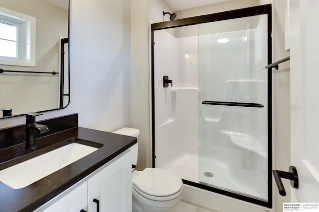 bathroom with a shower with door, vanity, and toilet