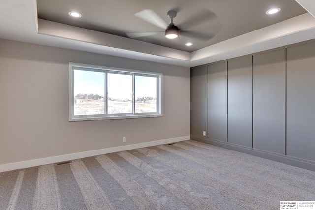 carpeted empty room featuring ceiling fan and a tray ceiling