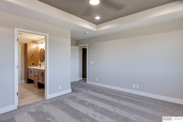 unfurnished bedroom with ceiling fan, ensuite bathroom, and light carpet