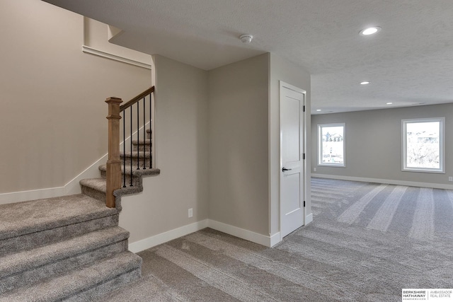 stairway featuring carpet floors and a textured ceiling