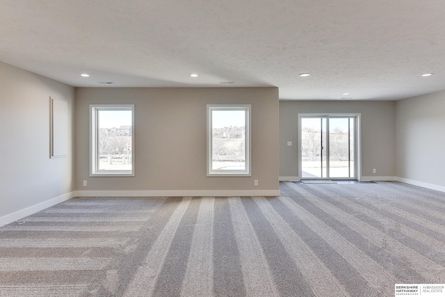 unfurnished room featuring plenty of natural light, light colored carpet, and a textured ceiling