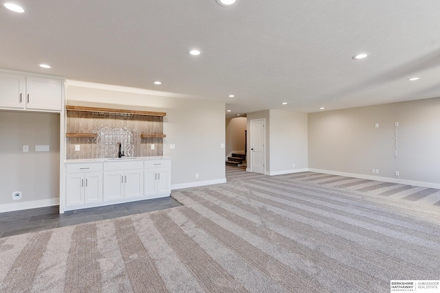 unfurnished living room with sink and light colored carpet