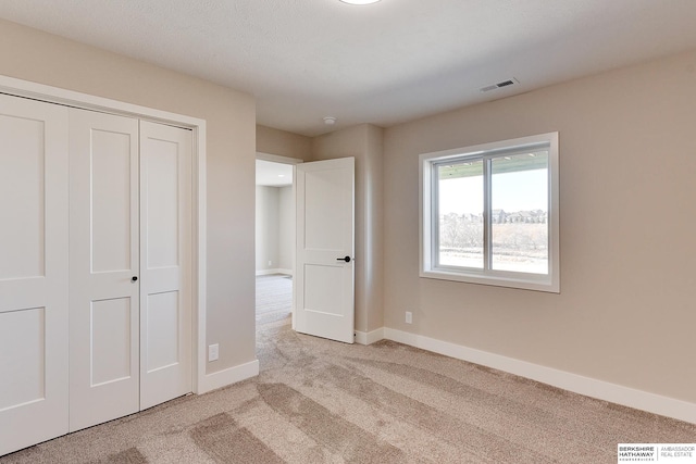 unfurnished bedroom with light carpet and a closet