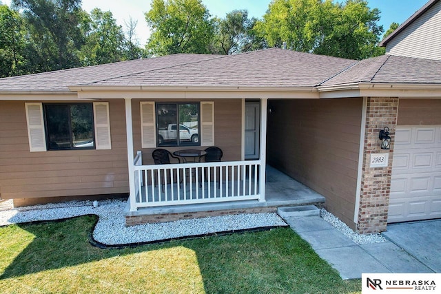 view of exterior entry with covered porch and a lawn