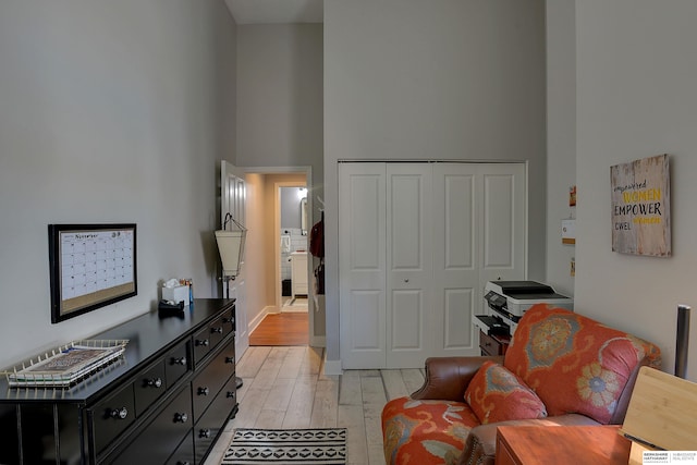 living area with light hardwood / wood-style floors and a high ceiling