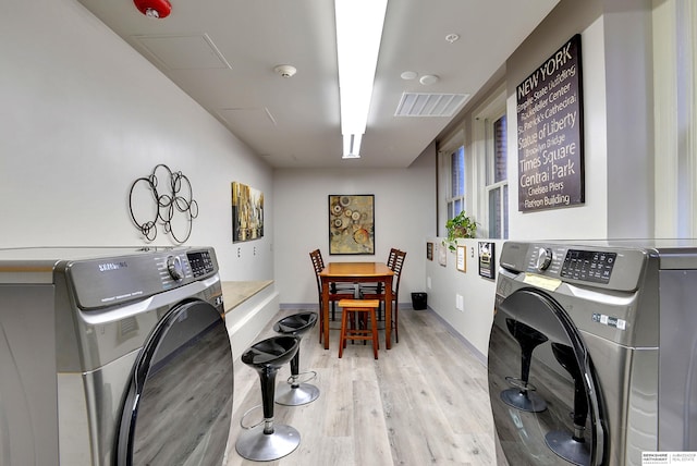 clothes washing area with light hardwood / wood-style floors and washing machine and dryer