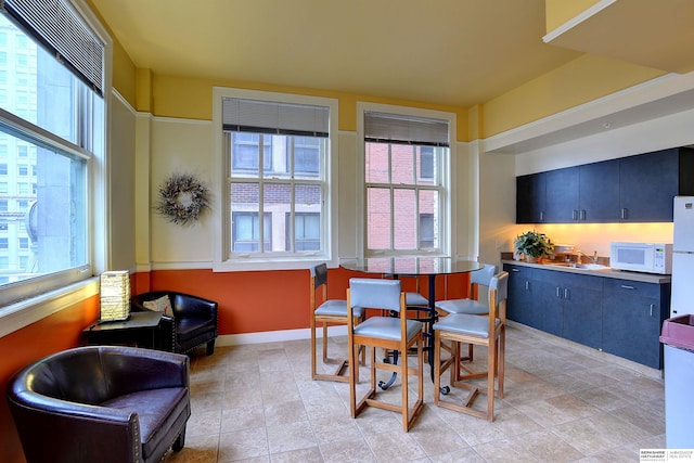 tiled dining space featuring a healthy amount of sunlight and sink