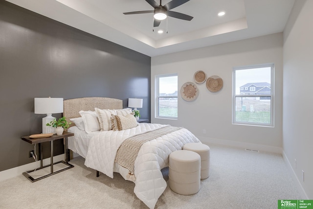 carpeted bedroom with a tray ceiling and ceiling fan