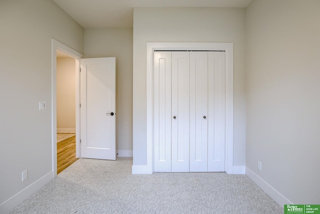 unfurnished bedroom with light carpet and a closet