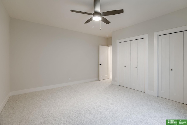 unfurnished bedroom with two closets, carpet floors, and ceiling fan