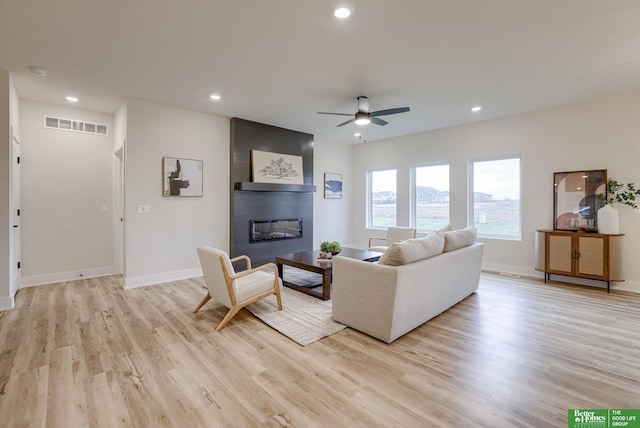 living room with light hardwood / wood-style floors, a fireplace, and ceiling fan