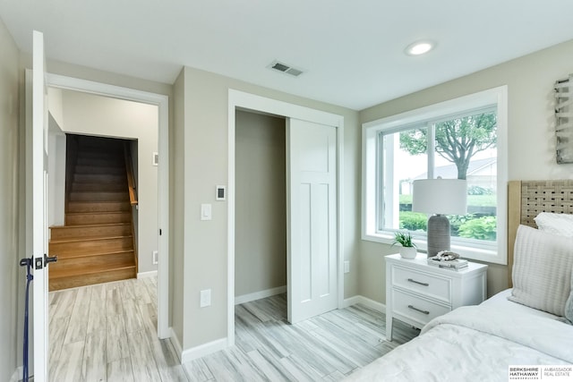 bedroom with light hardwood / wood-style floors and a closet