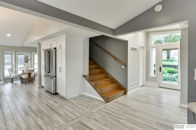 foyer with light hardwood / wood-style floors, lofted ceiling, and plenty of natural light